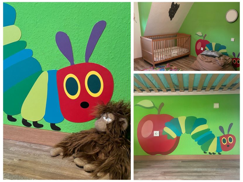 Grün gestrichene Kinderzimmerwand mit großem Wandbild der Raupe Nimmersatt und einem roten Apfel, inspiriert vom Kinderbuch. Daneben ein Gitterbett, ein Sitzsack und ein Plüschtier-Affe. Weitere Ausschnitte zeigen das Wandbild unter einem Hochbett sowie eine Detailaufnahme des Raupenkopfs.