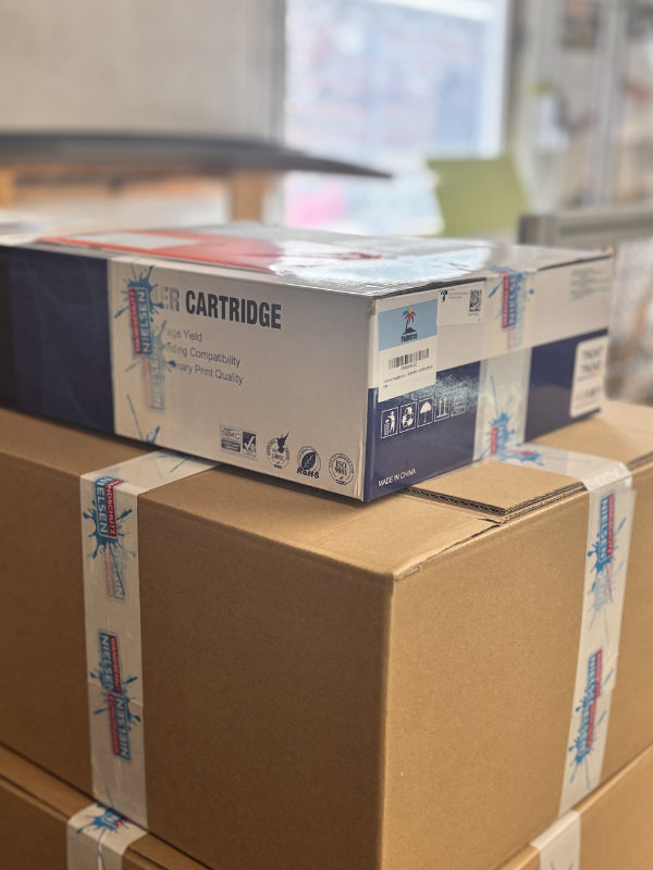Mehrere gestapelte Versandkartons, obenauf liegt eine Wandschutz Nielsen Sendung, verpackt in einem alten Karton aus einer Lieferung von Druckerpatronen in Originalverpackung.